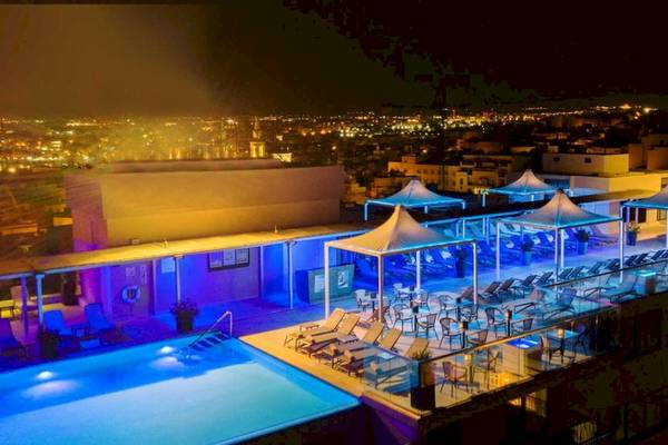 Nachtaufnahme der Dachterrasse des AX The Palace Hotels mit beleuchtetem Pool und Lounge-Bereichen