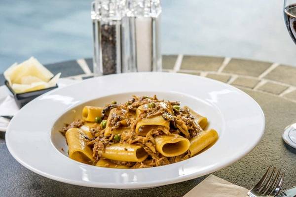 Ein Teller mit Penne in einer braunen Soße, serviert im AX The Palace Hotel.