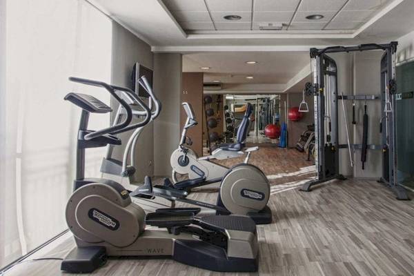 Fitnesscenter im AX The Palace Hotel mit Laufbändern, Ellipsentrainern und Hantelbank.