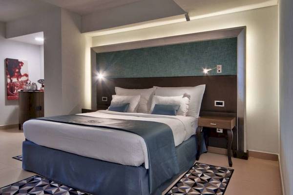Innenansicht eines Hotelzimmers im AX The Palace mit einem großen Bett, Dekor und Nachttischen.