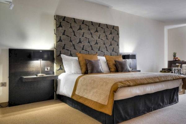 Schlafzimmer im AX The Palace Hotel mit großem Bett, dekorativen Kissen und Nachttischen.