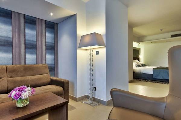 Innenansicht des AX The Palace Hotels mit Sofa, Tisch, Lampe und Schlafzimmer