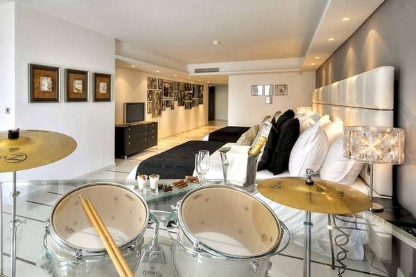 Schlafzimmer im AX The Palace Hotel mit einem Bett, weißen Kissen und einer Drum-Set auf einem Glastisch.