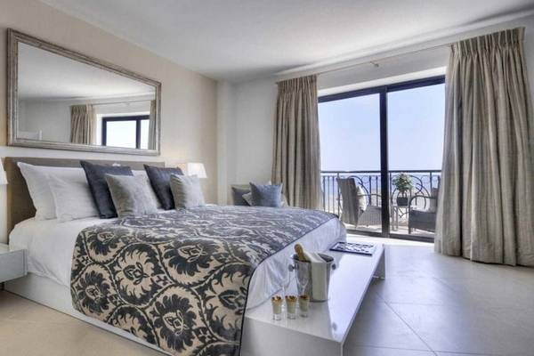 Schlafzimmer im AX The Palace Hotel mit einem großen Bett, vielen Kissen, und einem Balkon mit Meerblick.