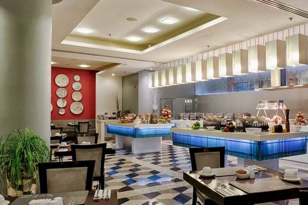 Innenansicht des Restaurants im AX The Palace Hotel mit Frühstücksbuffet, Tischen und Stühlen.