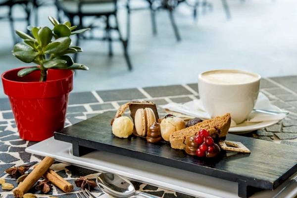Dessertplatte mit verschiedenen Leckereien, Kaffee und einer Pflanze im AX The Palace