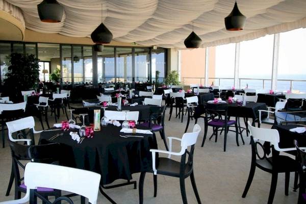 Innenansicht des Restaurants im AX The Palace Hotel mit vielen gedeckten Tischen und Meerblick.