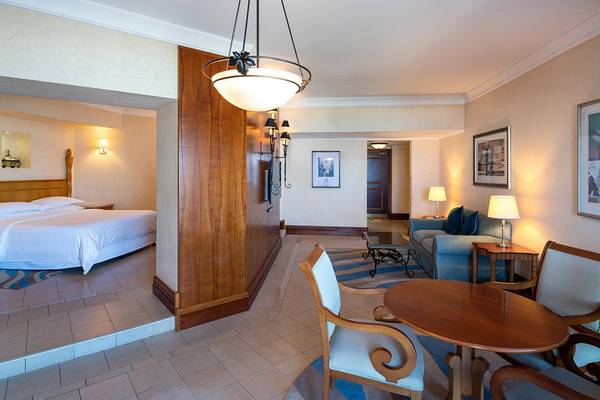Suite-Interieur im Sheraton Jumeirah Beach Resort mit Bett, Wohnzimmer und Tisch.