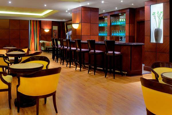Innenansicht der Bar im Sheraton Jumeirah Beach Resort mit Barhockern und Tischen.