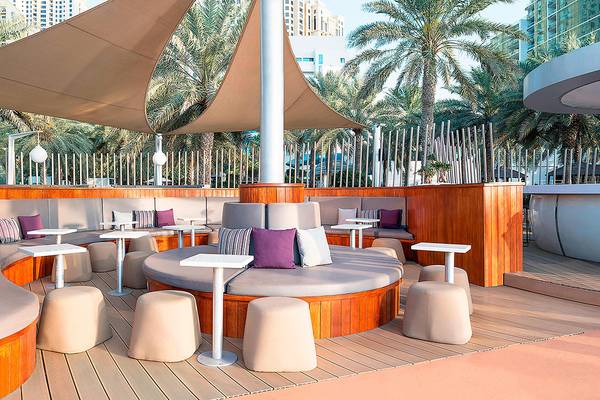 Terrasse des Sheraton Jumeirah Beach Resorts mit Loungemöbeln und Palmen im Hintergrund.