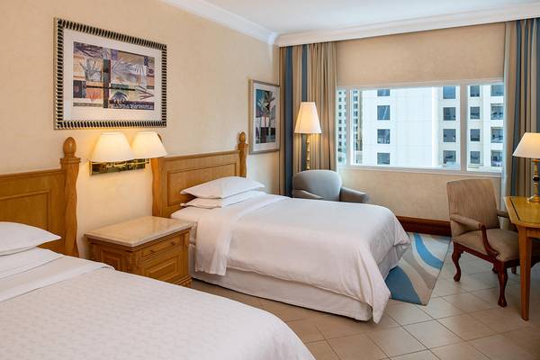 Zwei Betten im Sheraton Jumeirah Beach Resort Zimmer mit Blick auf die Stadt.