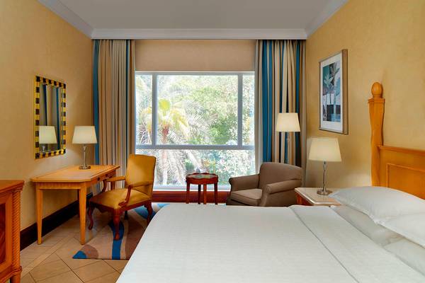 Hotelzimmer im Sheraton Jumeirah Beach Resort mit großem Bett, Schreibtisch und Fenstern.