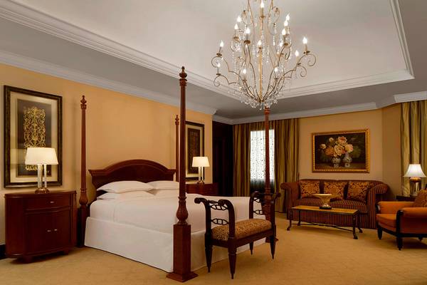 Schlafzimmer im Sheraton Jumeirah Beach Resort mit einem großen Bett, Kronleuchter, und eleganter Einrichtung.