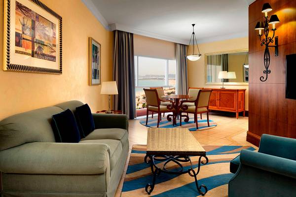 Wohnbereich des Sheraton Jumeirah Beach Resorts mit einem Sofa, Tisch und Blick auf das Meer.