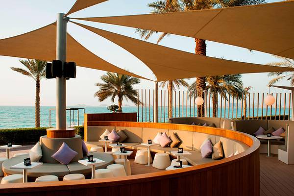 Außenterrasse des Sheraton Jumeirah Beach Resorts mit Blick auf das Meer und Palmen