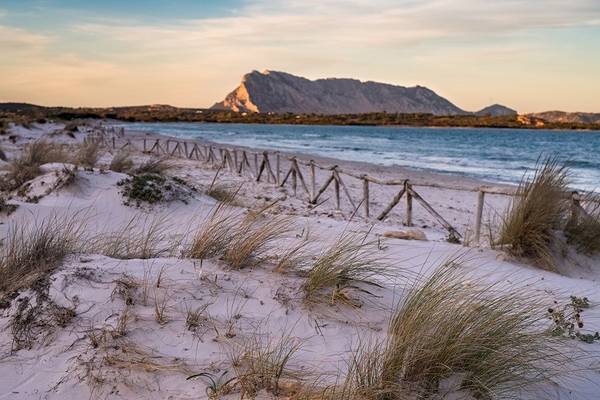 Hotel Ollastu Resort Strand bei Sonnenuntergang mit Dünen und Felsen im Hintergrund