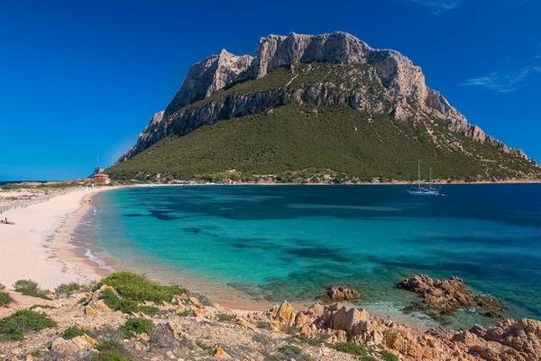 Hotel Ollastu Resort Strand mit kristallklarem Wasser und Felsen im Hintergrund