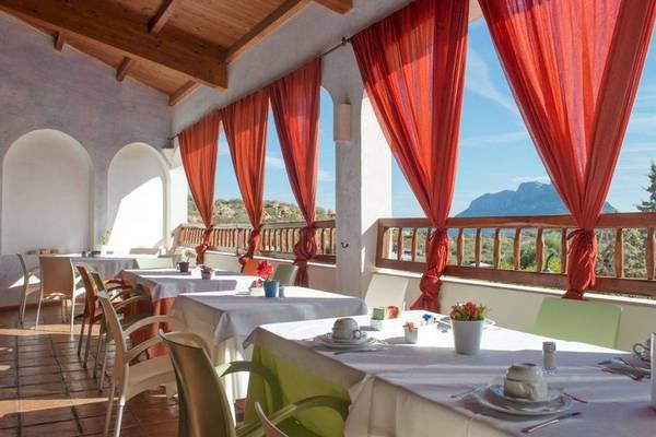 Terrasse des Hotel Ollastu Resort mit roten Vorhängen und Blick auf die Berge