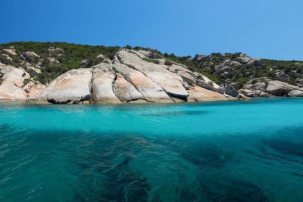 Klares blaues Wasser und Felsen am Strand des Hotel Ollastu Resort.