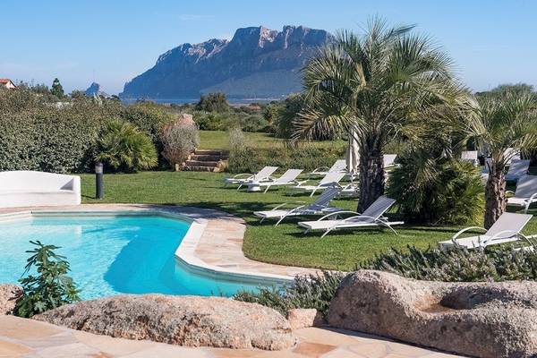 Außenbereich des Hotel Ollastu Resort mit Swimmingpool und Liegestühlen