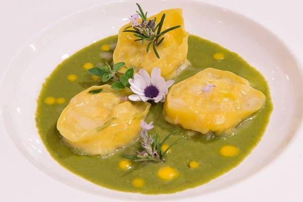 Gericht in einem weißen Teller mit grüner Sauce und Blumen