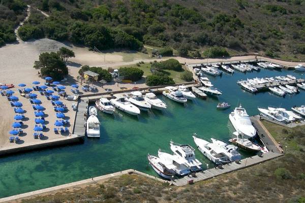 Luftaufnahme des Ollastu Resort Marina mit vielen geparkten Booten und blauen Sonnenschirmen.