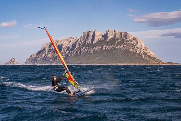 Windsurfer vor einer Insel mit Bergen im Hintergrund