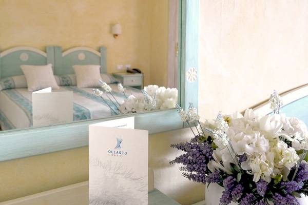 Ein Schlafzimmer mit Bett und Spiegel im Ollastu Resort Hotel.