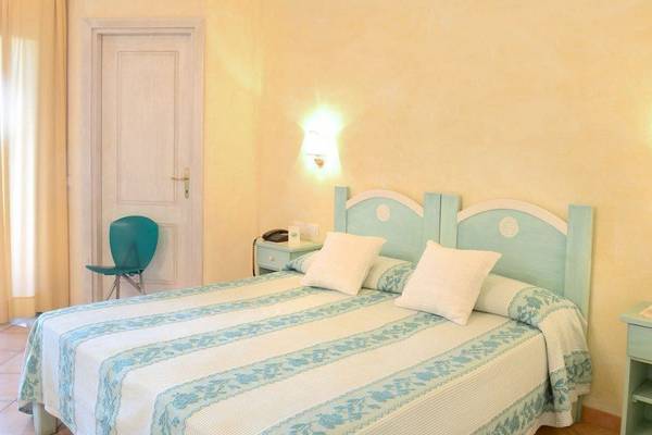 Doppelbettzimmer im Hotel Ollastu Resort mit blauem Kopfteil und gelben Wänden.