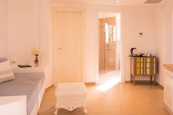 Innenansicht eines Zimmers im Hotel Ollastu Resort mit Bett, Tisch, Schrank und Dusche