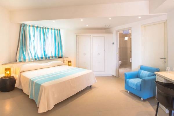 Schlafzimmer im Hotel Ollastu Resort mit Doppelbett, blauer Couch, Nachttischen und Lampen.