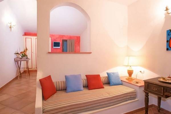 Innenbereich des Hotel Ollastu Resort mit einer Sofaecke, Kissen und einem Tisch