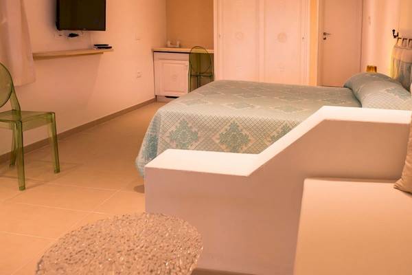 Hotel Ollastu Resort Zimmer mit Bett, Stuhl und Fernseher.
