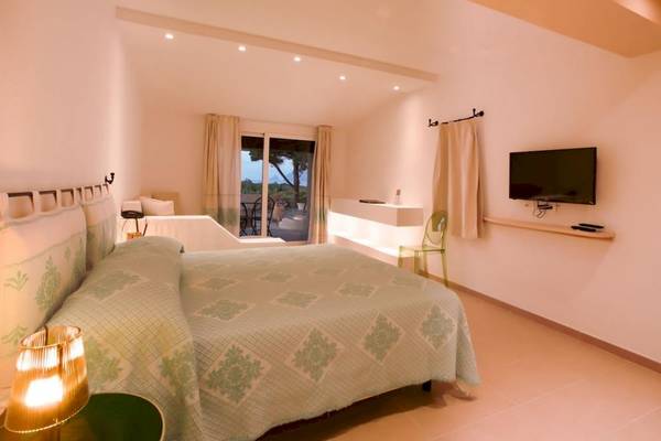 Schlafzimmer mit Doppelbett, Fernseher und Tischlampe.