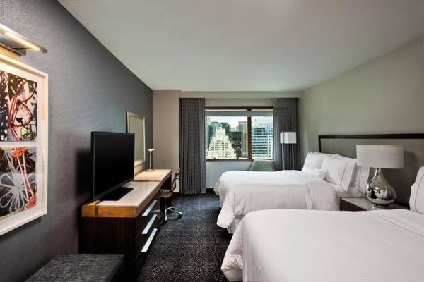 Hotelzimmer mit zwei Betten und Arbeitsbereich, Flachbildfernseher und Schreibtisch.