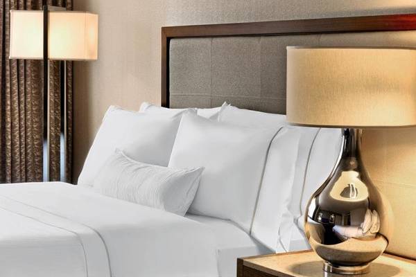 Bett im Zimmer des Westin New York at Times Square mit weißen Laken und Kissen.