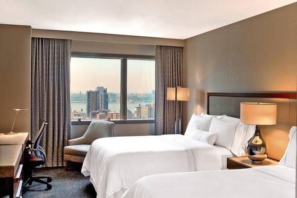 Zimmer im Westin New York at Times Square Hotel mit zwei Betten, Schreibtisch und Blick auf die Stadt.