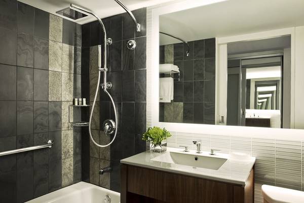 Badezimmer im Westin New York at Times Square Hotel mit Badewanne, Dusche, Waschbecken und Spiegel.
