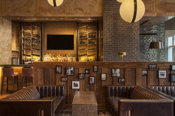 Innenansicht der Bar im Westin New York at Times Square Hotel mit Barhockern, Ledersofas und einer Bartheken mit Fernseher.