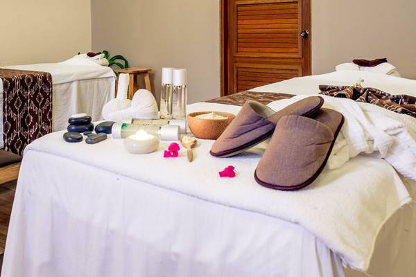 Behandlungsraum im Kudafushi Resort & Spa mit zwei Massagetischen, weißen Handtüchern und verschiedenen Wellnessartikeln.