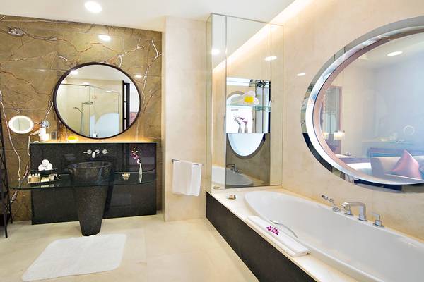 Badezimmer im Al Raha Beach Hotel mit Badewanne, Spiegeln und Waschbecken.