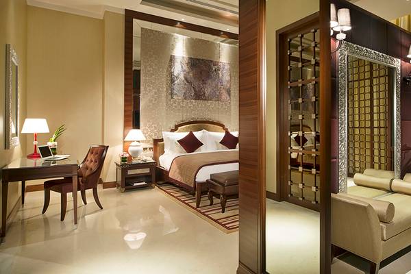 Innenansicht eines Zimmers im Al Raha Beach Hotel mit Bett, Schreibtisch und Möbeln.