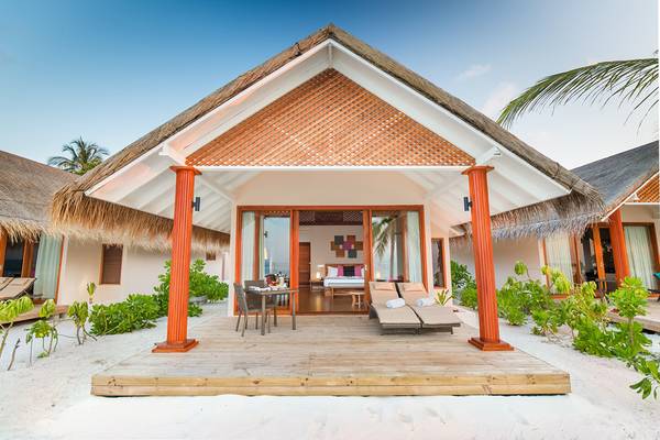 Außenansicht des Kudafushi Resort & Spa Ferienhauses mit Terrasse, Tisch und Stühlen.