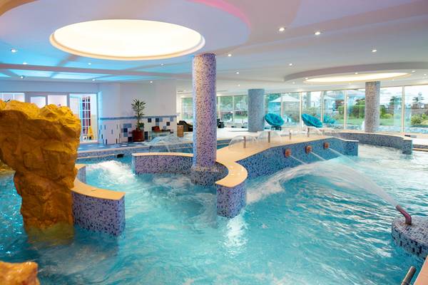 Innenpool des Al Raha Beach Hotel mit Wasserfällen und Säulen.