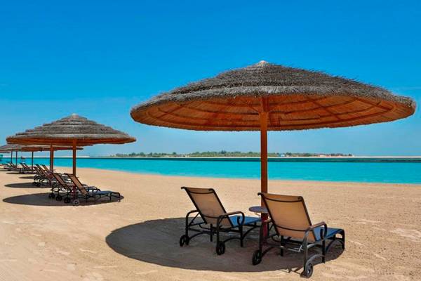 Strand des Al Raha Beach Hotels mit Liegestühlen und Sonnenschirmen am Wasser