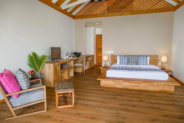 Innenansicht eines Schlafzimmers im Kudafushi Resort & Spa mit Holzboden, Bett, Nachttischen und Fernseher.