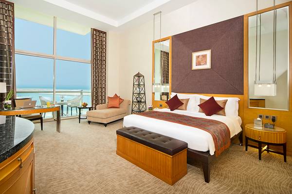 Suite-Zimmer im Al Raha Beach Hotel mit Meerblick, großem Bett, Wohnzimmerbereich und Schreibtisch