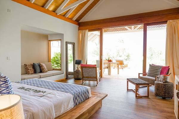 Schlafzimmer im Kudafushi Resort & Spa mit Bett, Möbeln und offenem Balkon