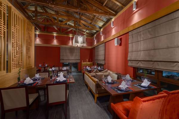 Innenbereich des Rixos Premium Tekirova Hotels, zeigt ein stilvolles Restaurant mit roten Wänden und Holzbalken.