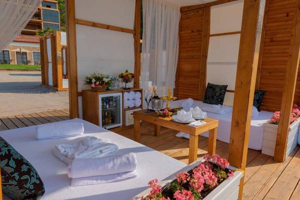 Terrassenbereich im Rixos Premium Tekirova Hotel mit zwei Betten, Tisch, Blumen und Dekor